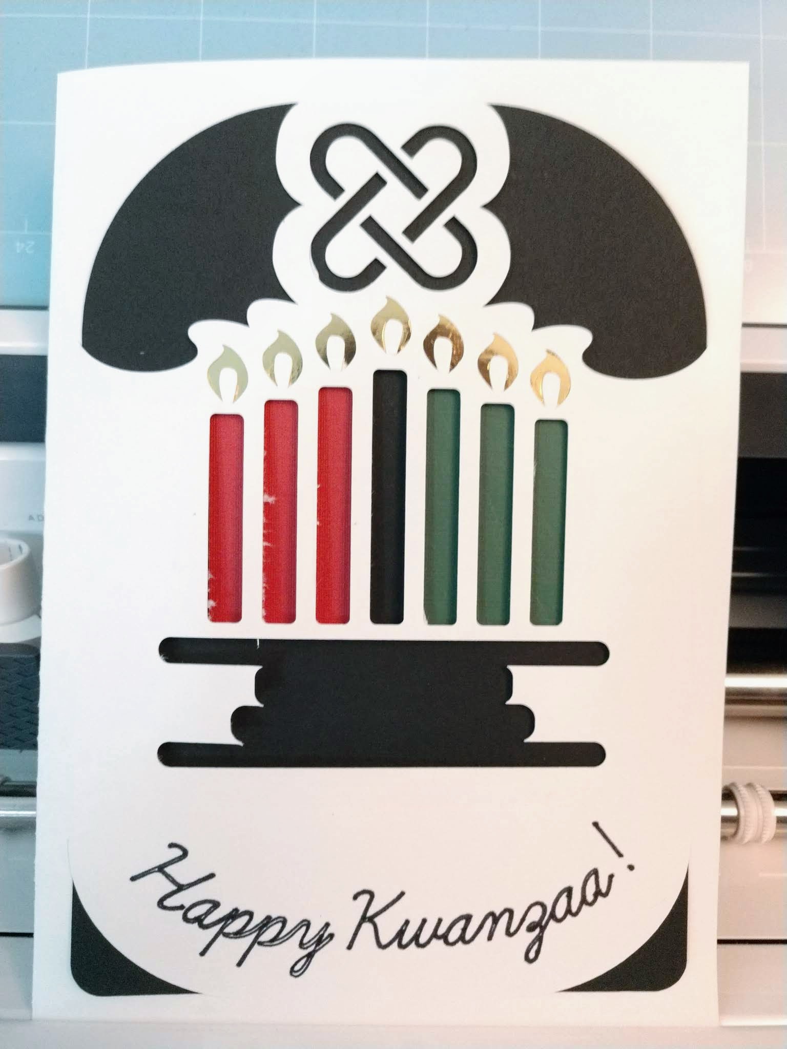 Stylized kinara with mishumaa saba in red, black, and green, with gold flames, and umoja above