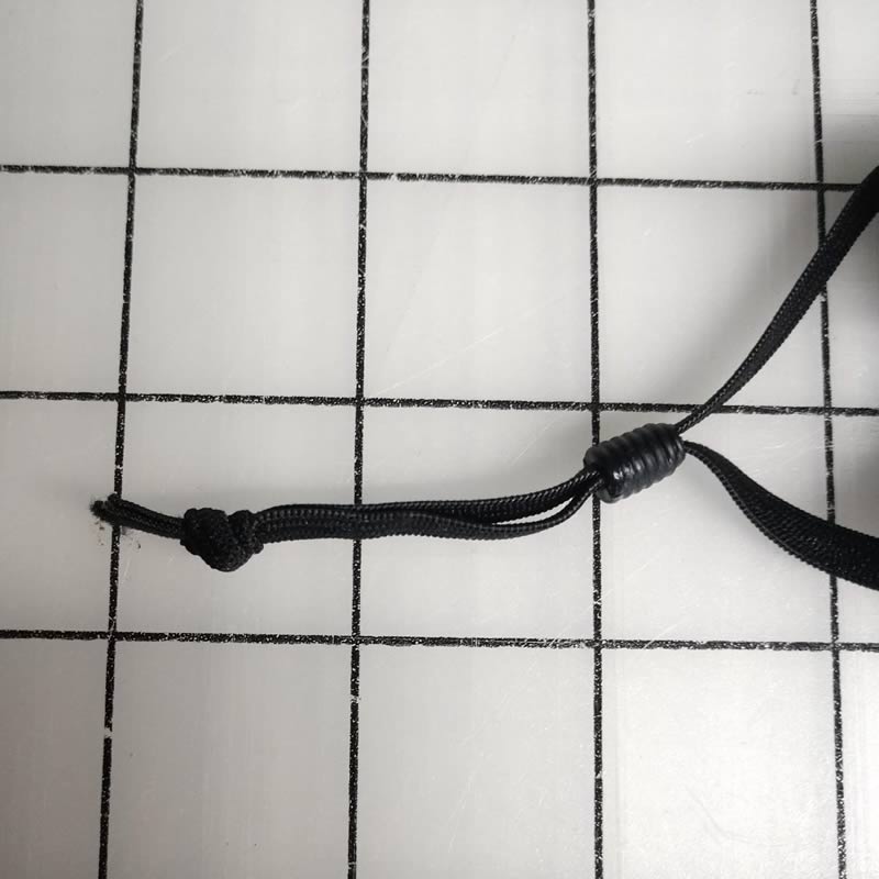 Tie a knot in the elastic ends so that the cord stopper is between the mask casing and the knot. This will keep the cord stopper from getting lost. 